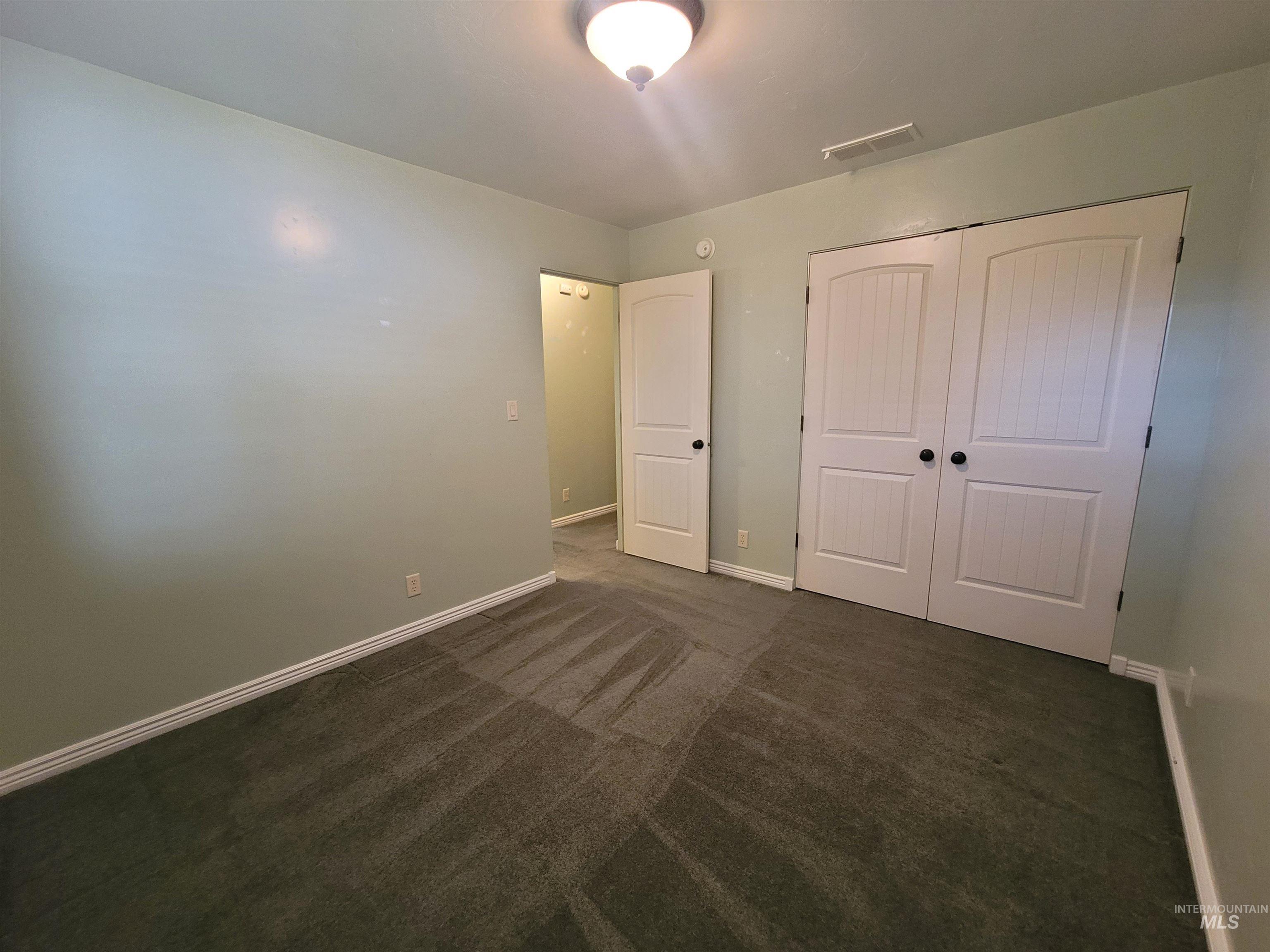 Unfurnished bedroom featuring dark carpet and a closet