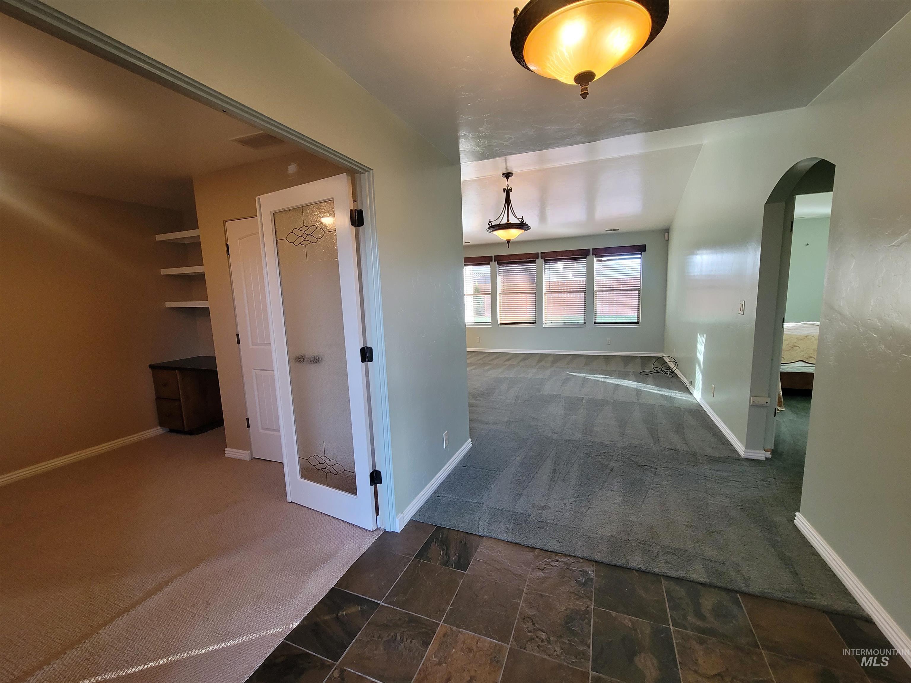 Hallway with dark carpet and arched walkways