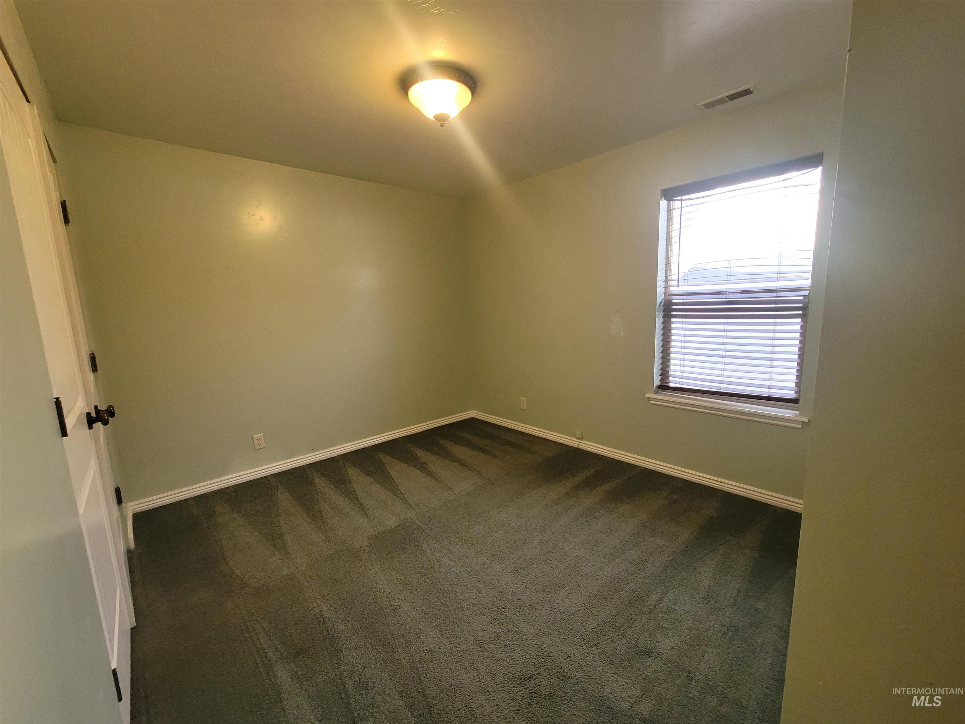 Empty room with dark colored carpet and baseboards