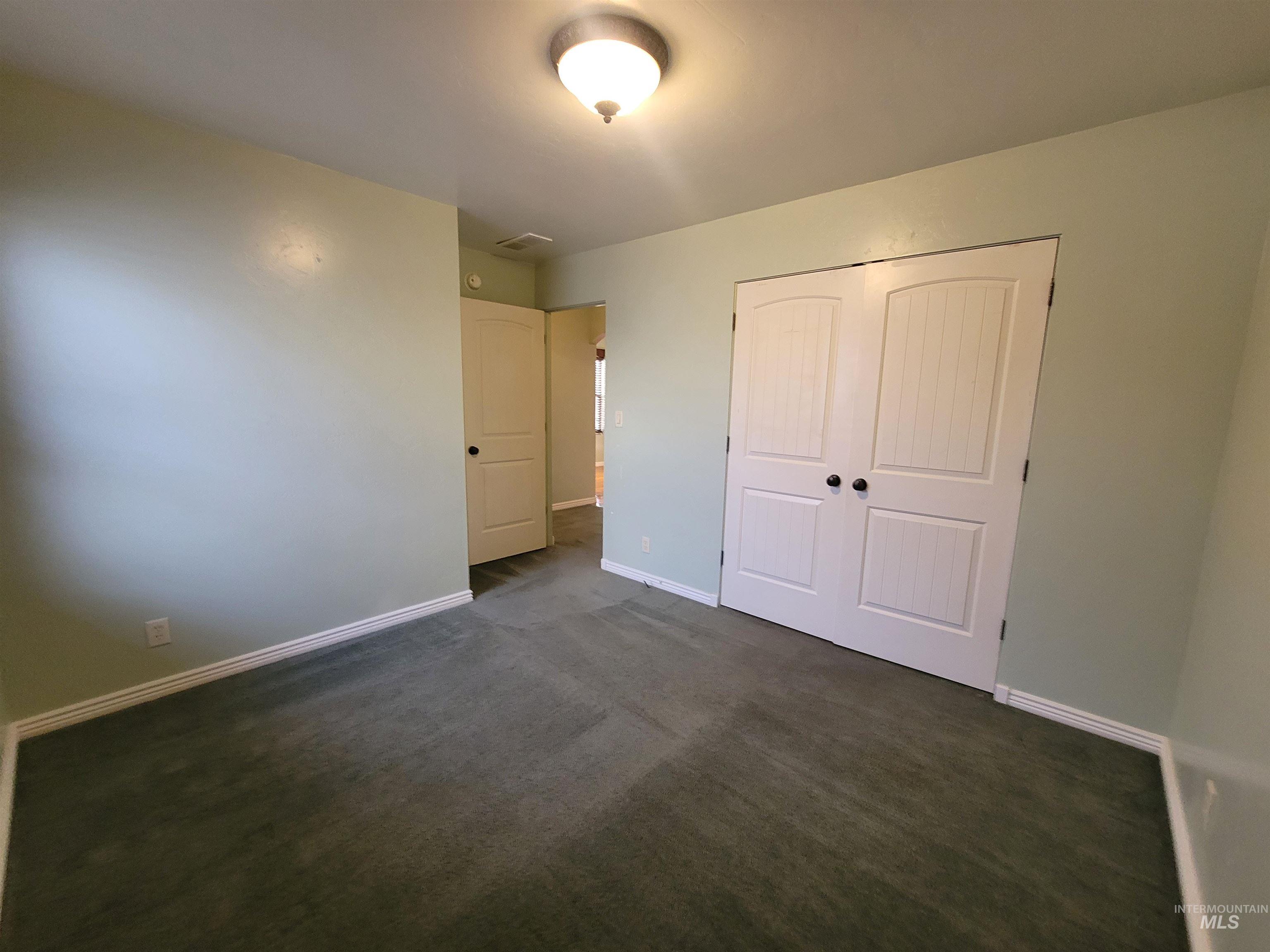 Unfurnished bedroom with dark carpet and a closet