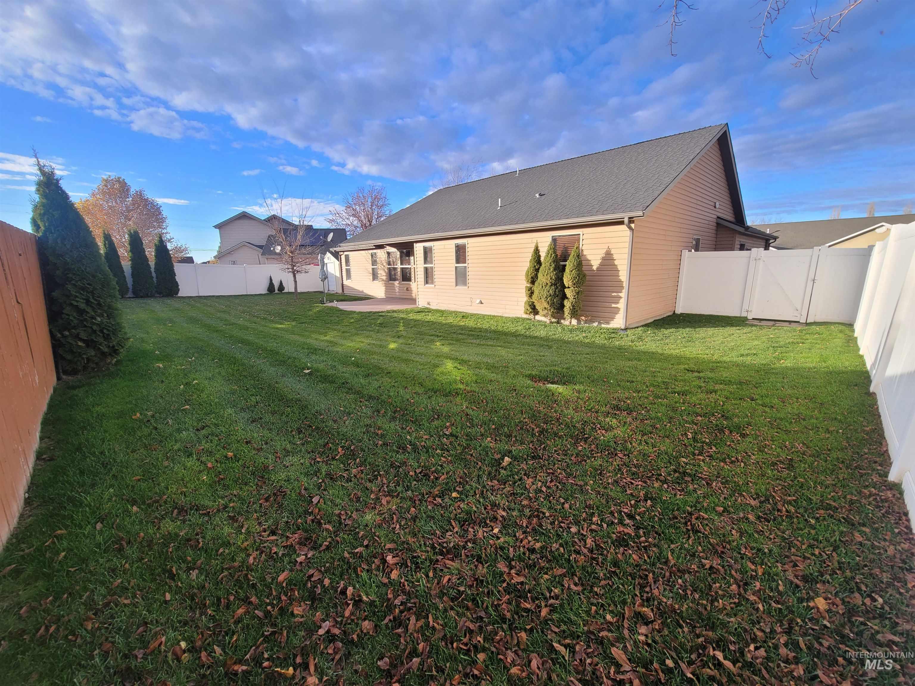 Rear view of house featuring a fenced backyard, a patio area, and a gate