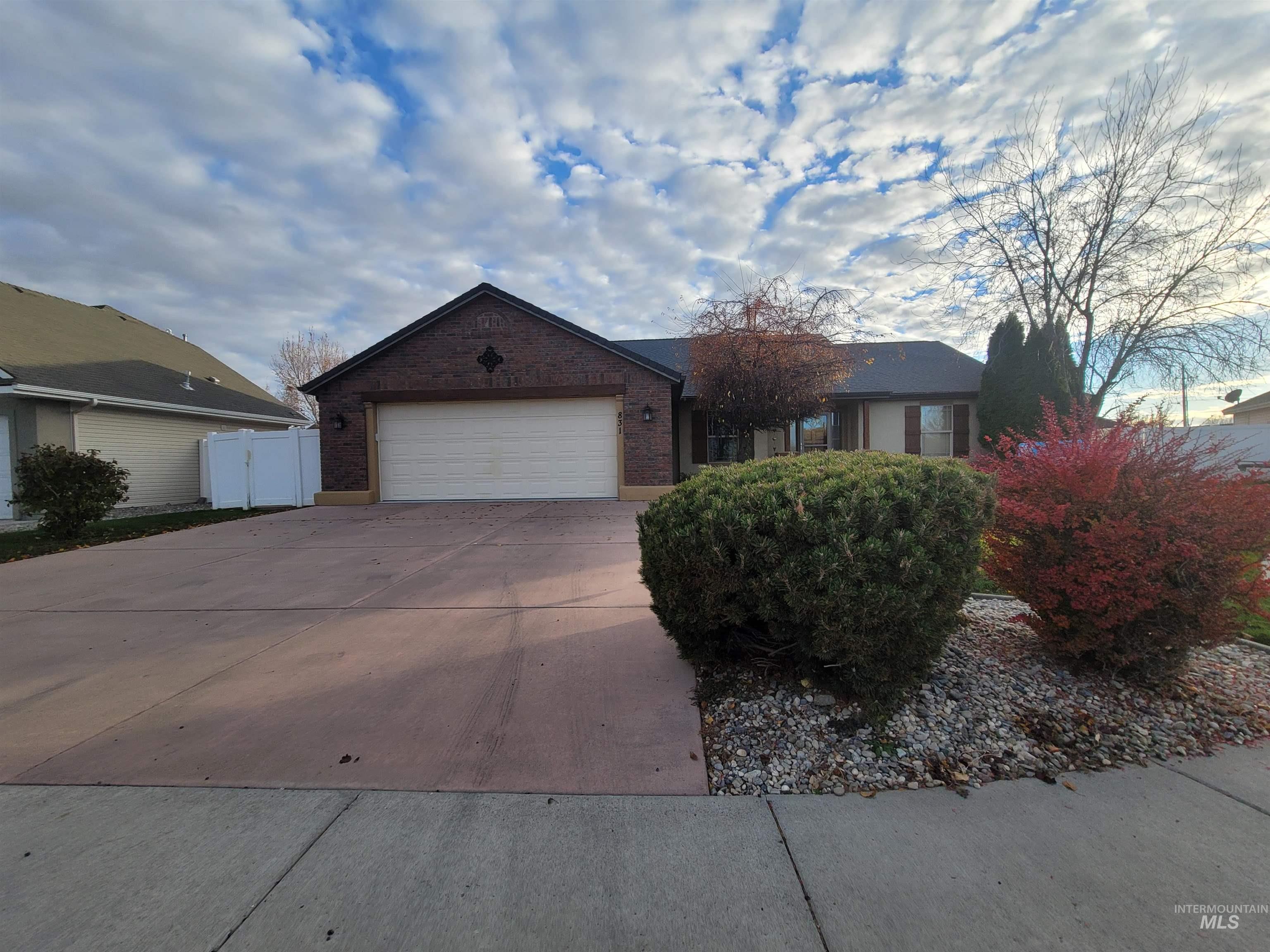 Single story home featuring a garage, concrete driveway, and brick siding