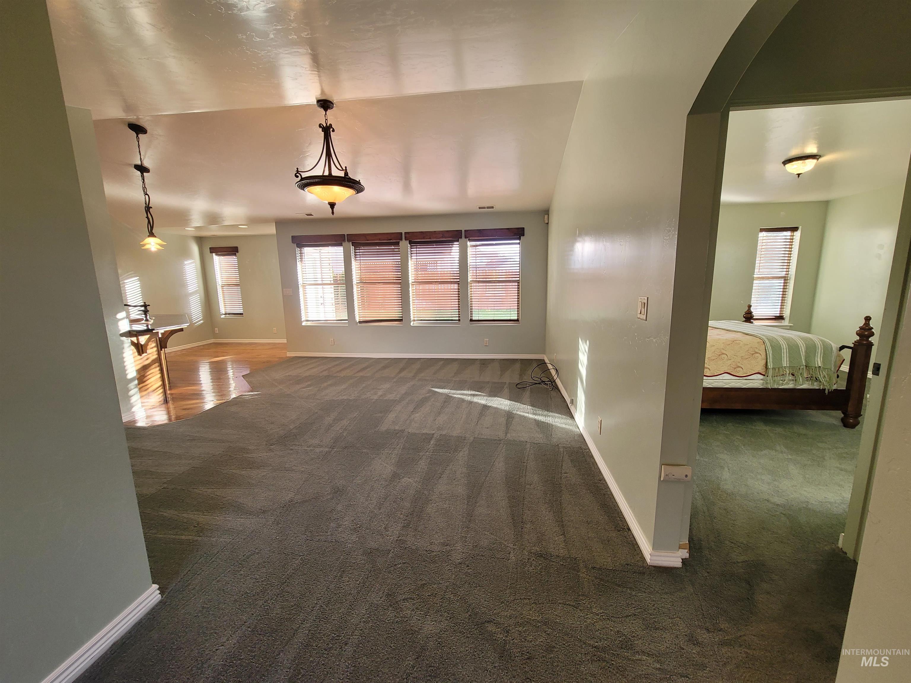 Unfurnished living room with dark colored carpet and arched walkways