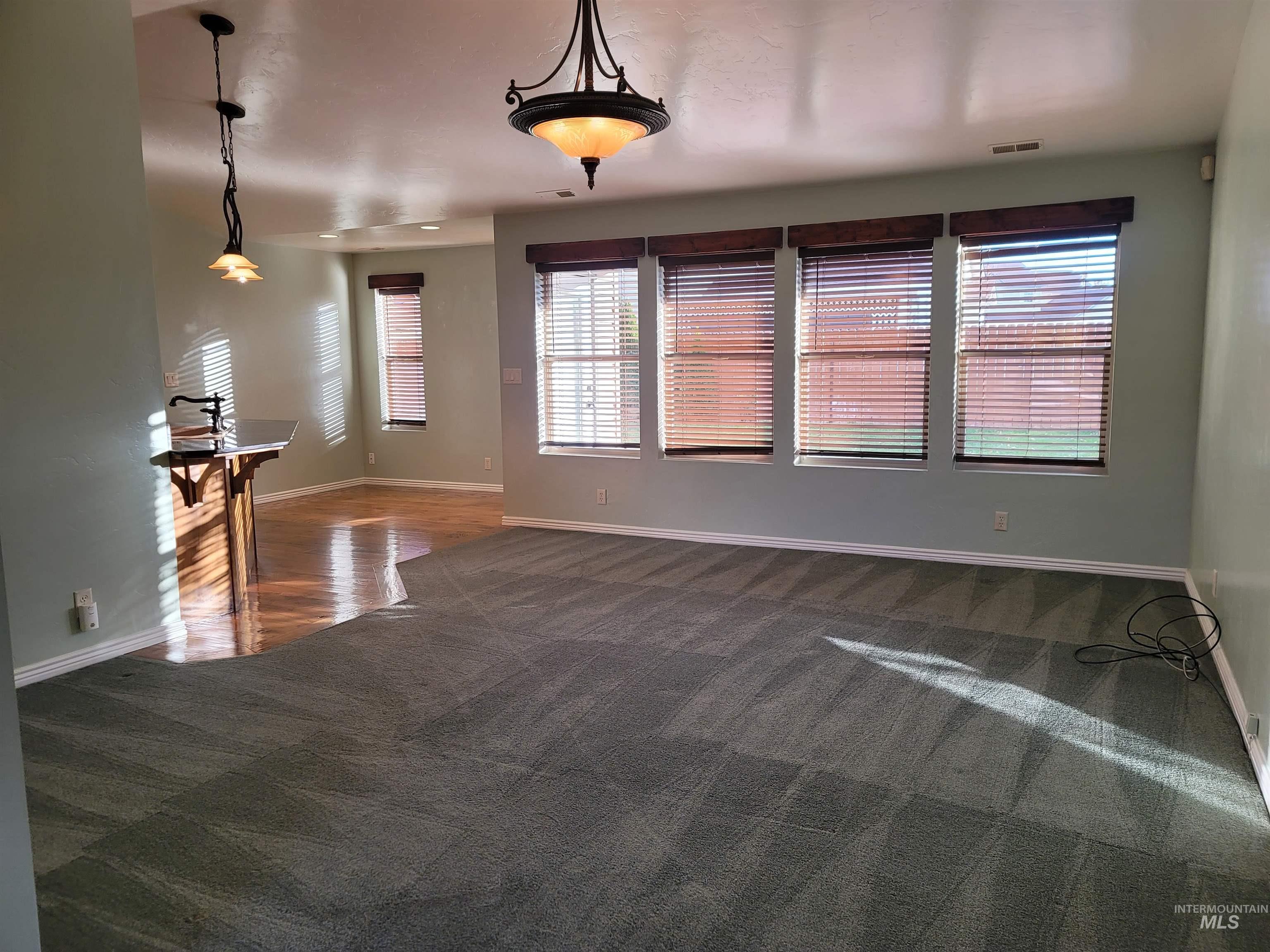 Unfurnished living room with healthy amount of natural light and dark carpet