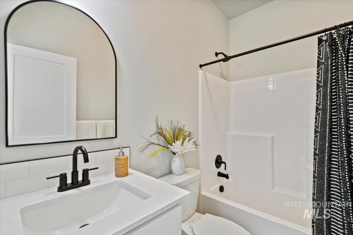 Bathroom with shower / bath combination with curtain, vanity, and decorative backsplash