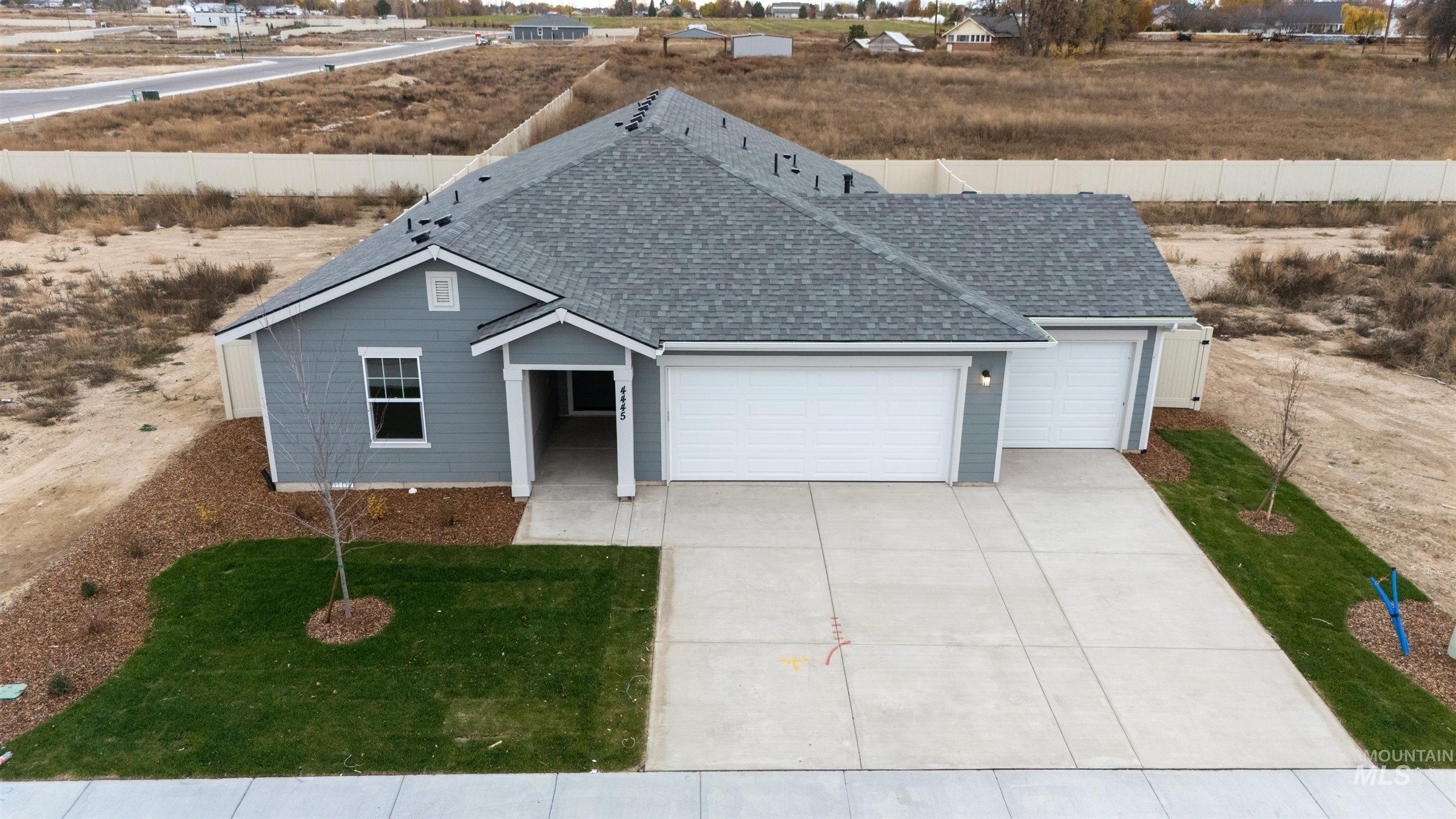 View of front of property featuring roof with shingles, an attached garage, concrete driveway, and a front lawn