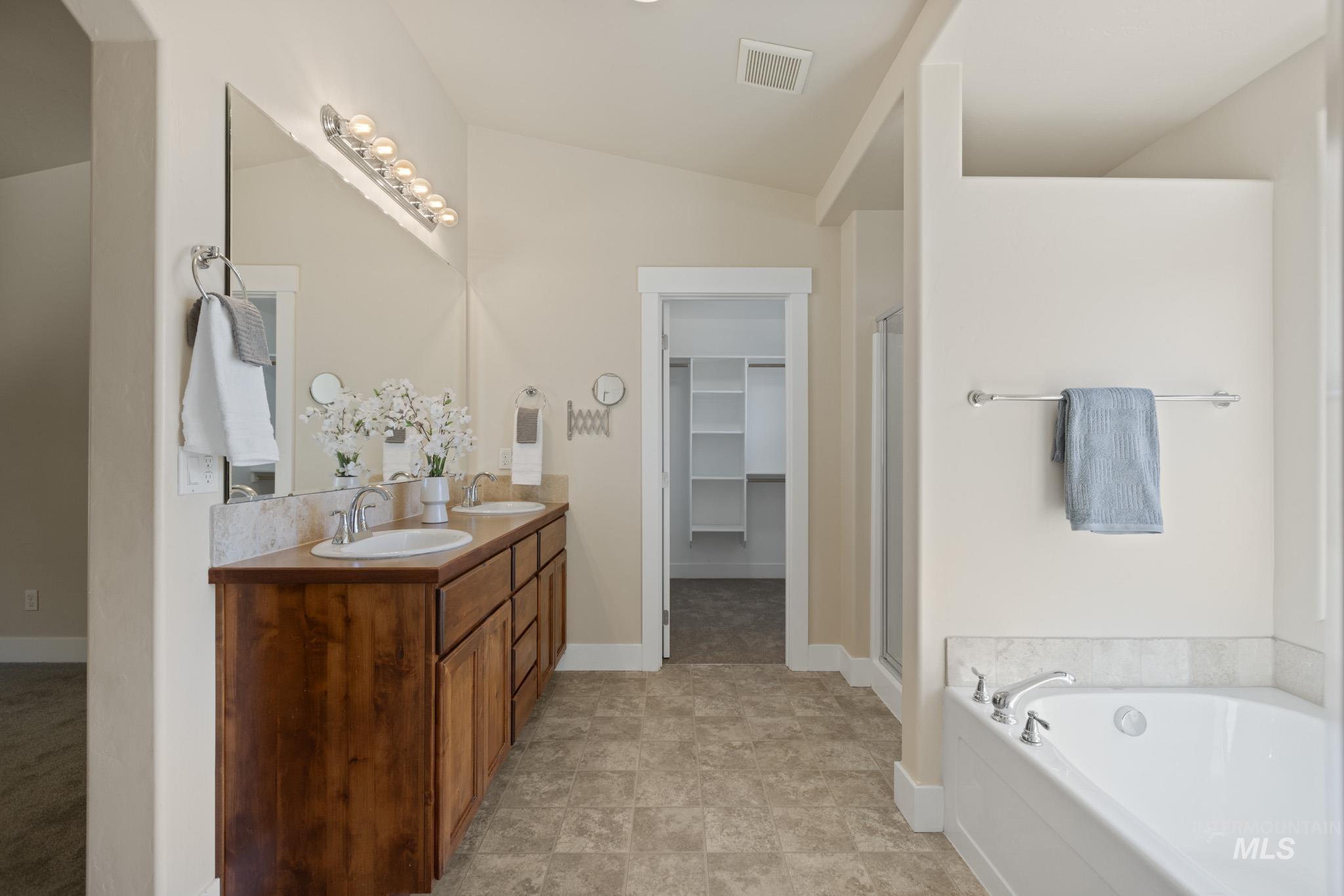 Full bathroom featuring double vanity, a garden tub, a stall shower and 2 walk in closets