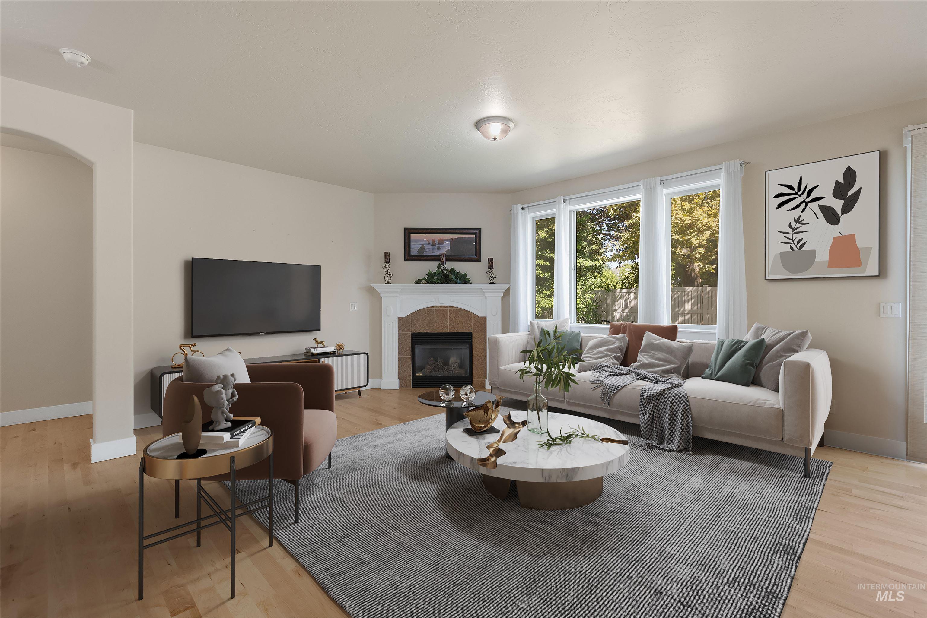 Living room featuring light wood finished floors, a fireplace, and arched walkways