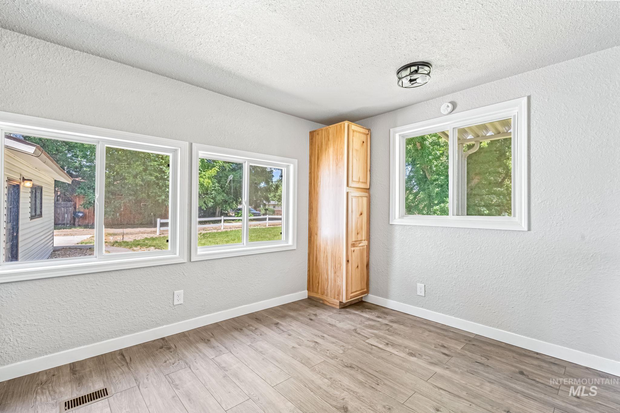 Spare room featuring plenty of natural light, a textured wall, a textured ceiling, and light wood-style flooring