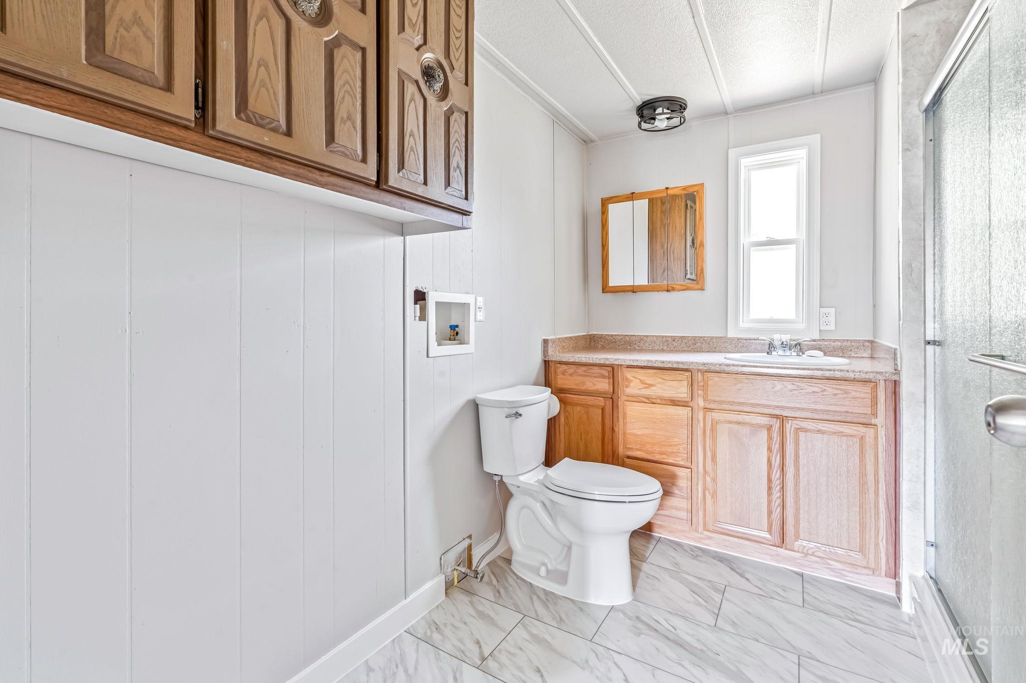 Bathroom featuring vanity, a shower stall, marble look tiles, and a textured ceiling