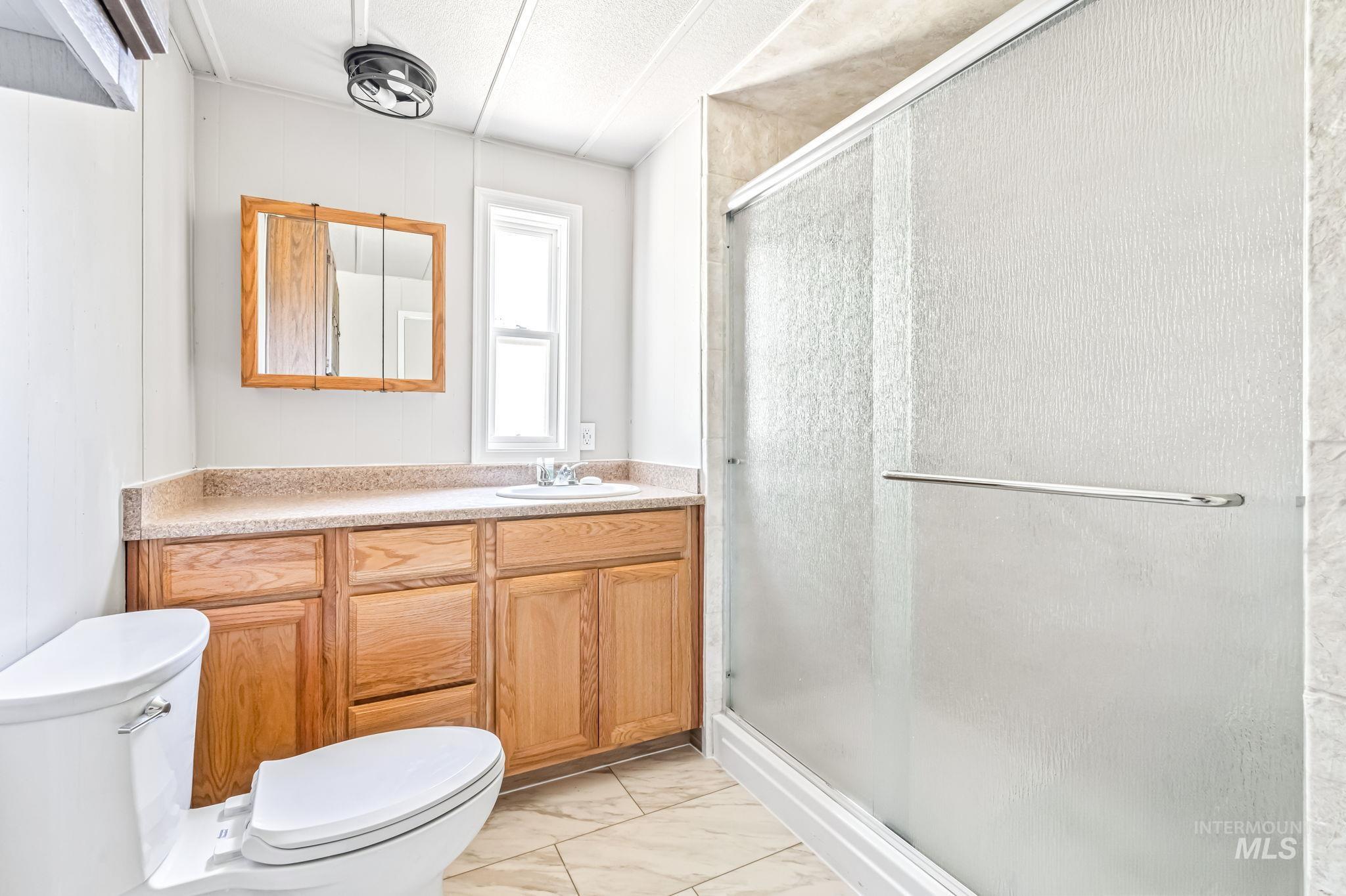 Bathroom with marble finish flooring, vanity, and a stall shower