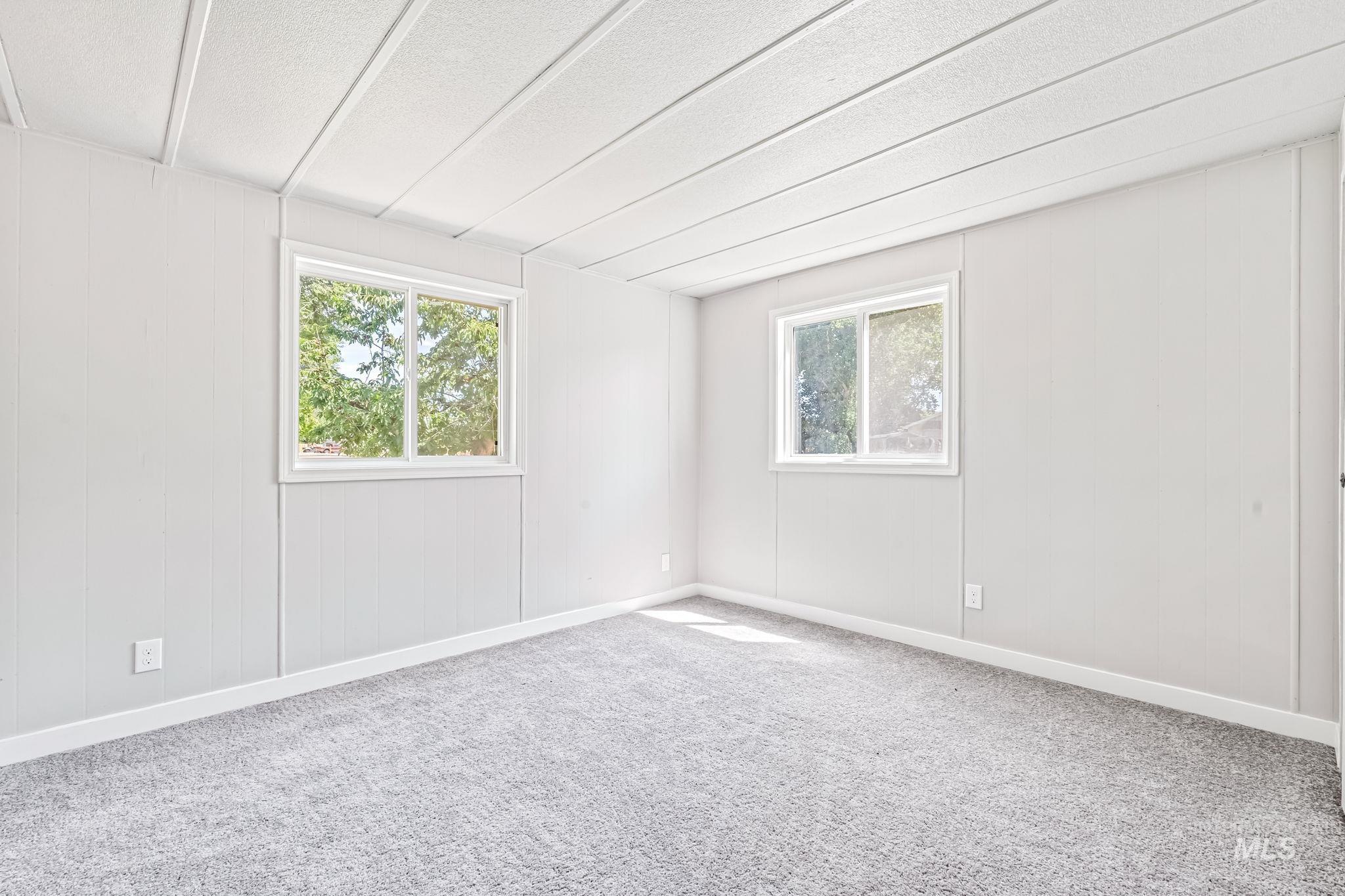 Carpeted spare room with plenty of natural light and a textured ceiling