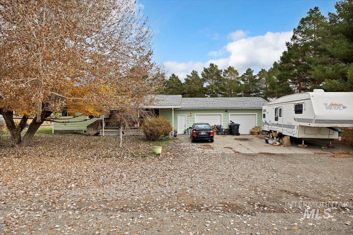 View of front of house with driveway, an attached garage, and view of scattered trees