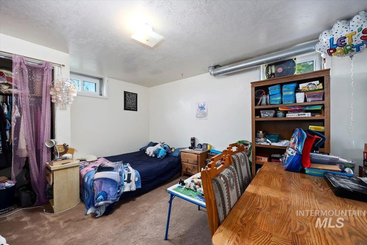 Carpeted bedroom featuring multiple windows and a textured ceiling