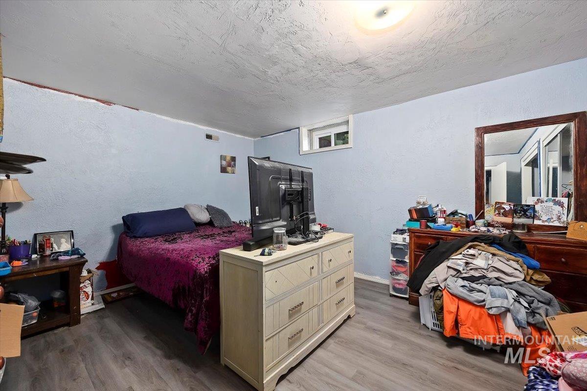 Bedroom with a textured wall, light wood-style floors, and a textured ceiling