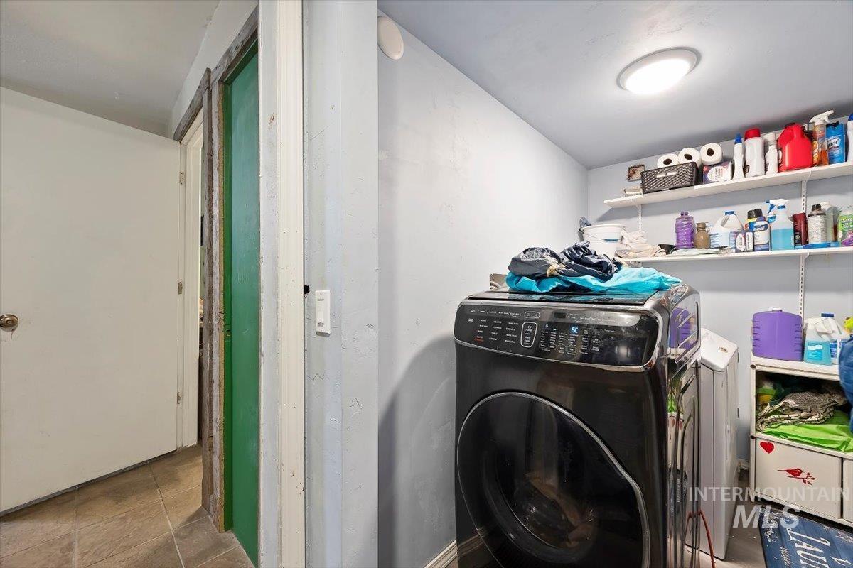 Laundry room with washer and clothes dryer and tile patterned flooring