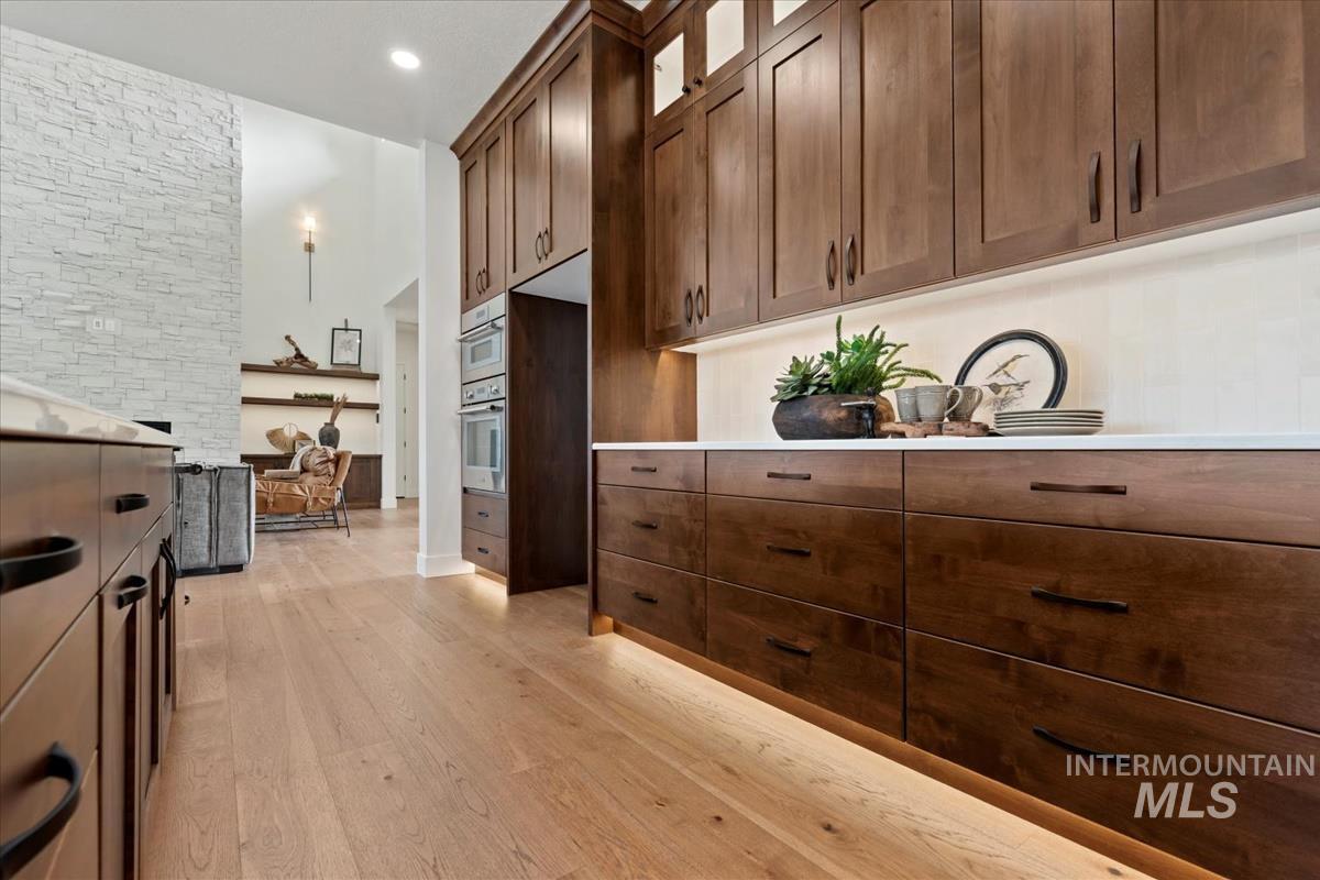 Kitchen with glass insert cabinets, light countertops, light wood-style floors, a towering ceiling, and recessed lighting
