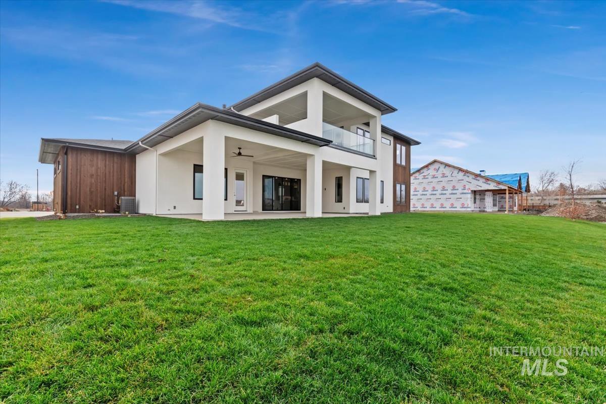 Rear view of property with a patio area, a yard, ceiling fan, and a balcony
