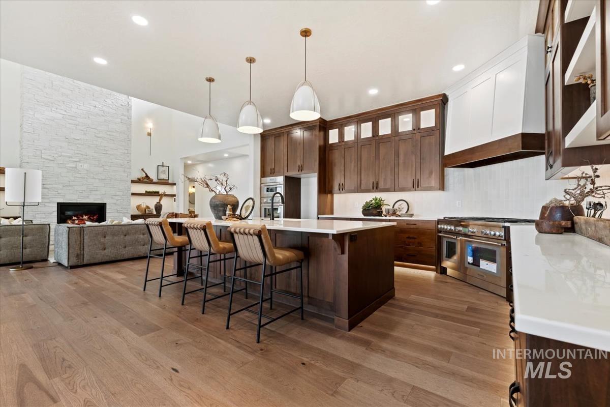 Kitchen featuring a kitchen bar, custom exhaust hood, an island with sink, open floor plan, and pendant lighting