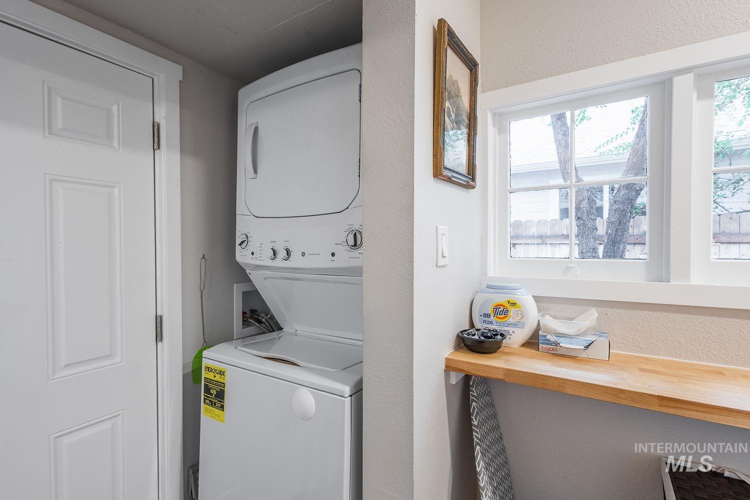 Laundry area featuring a textured wall and stacked washer and clothes dryer