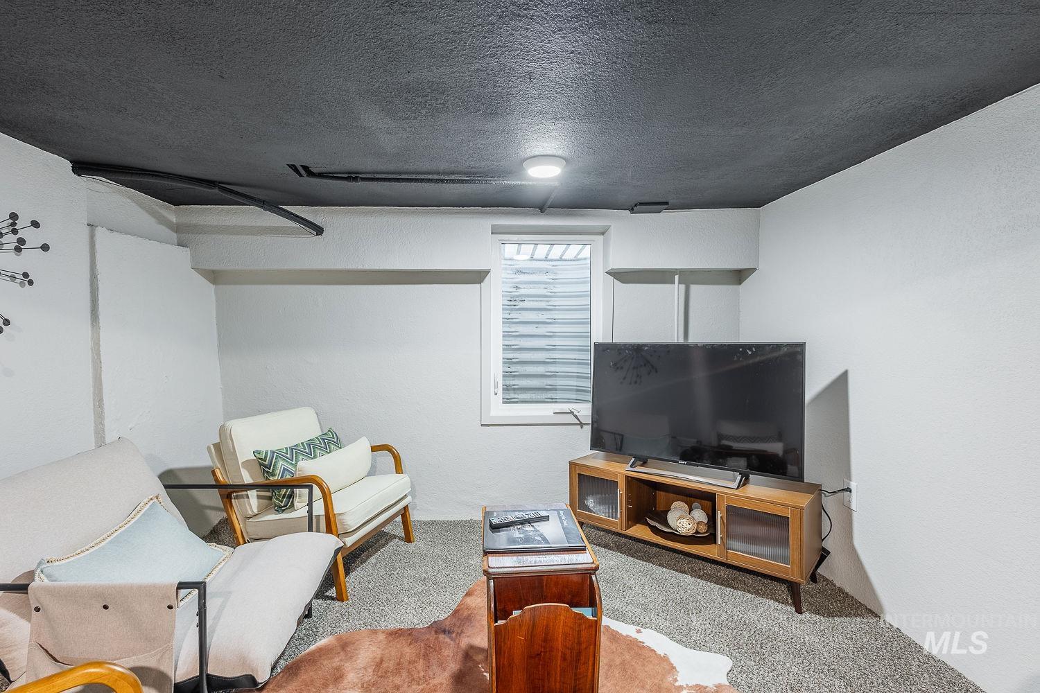 Living area with carpet floors, a textured ceiling, and a textured wall