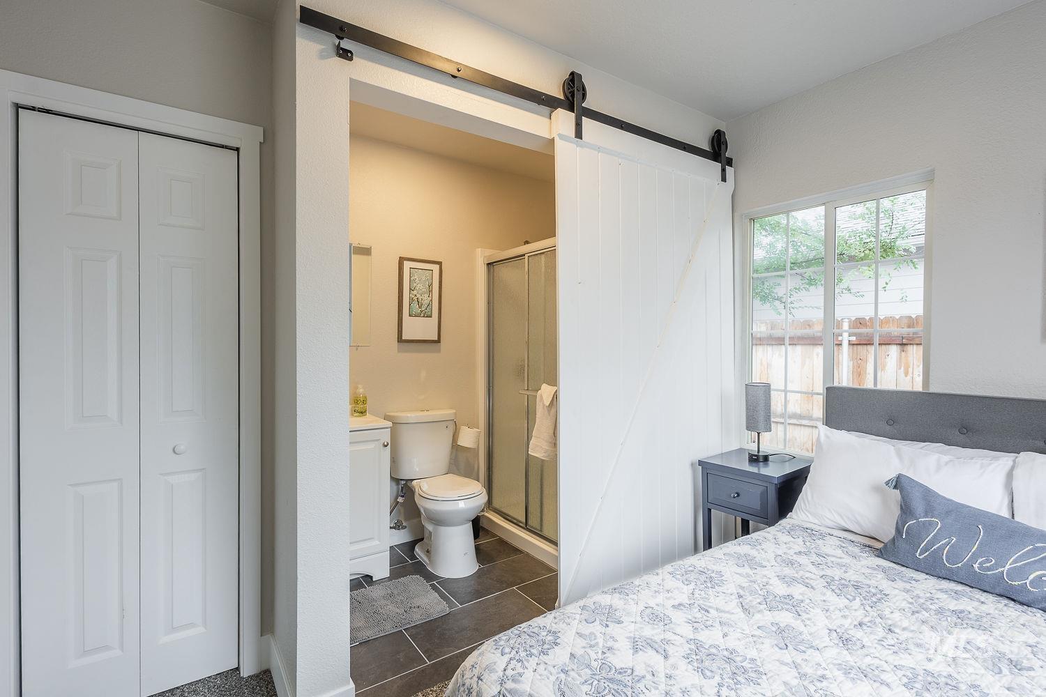 Bedroom featuring a barn door, connected bathroom, a closet, and dark tile patterned floors