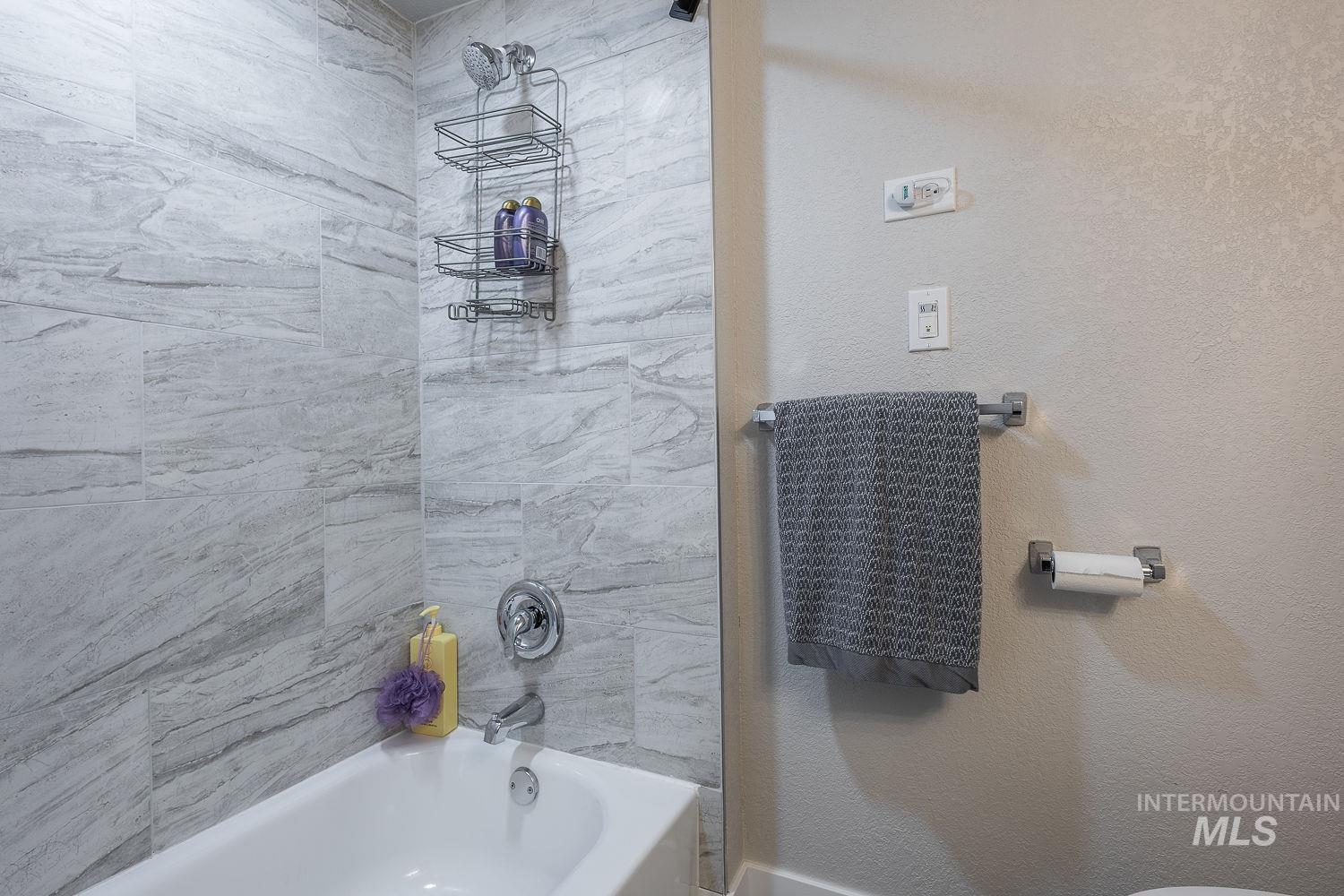Full bath featuring a textured wall and bathtub / shower combination