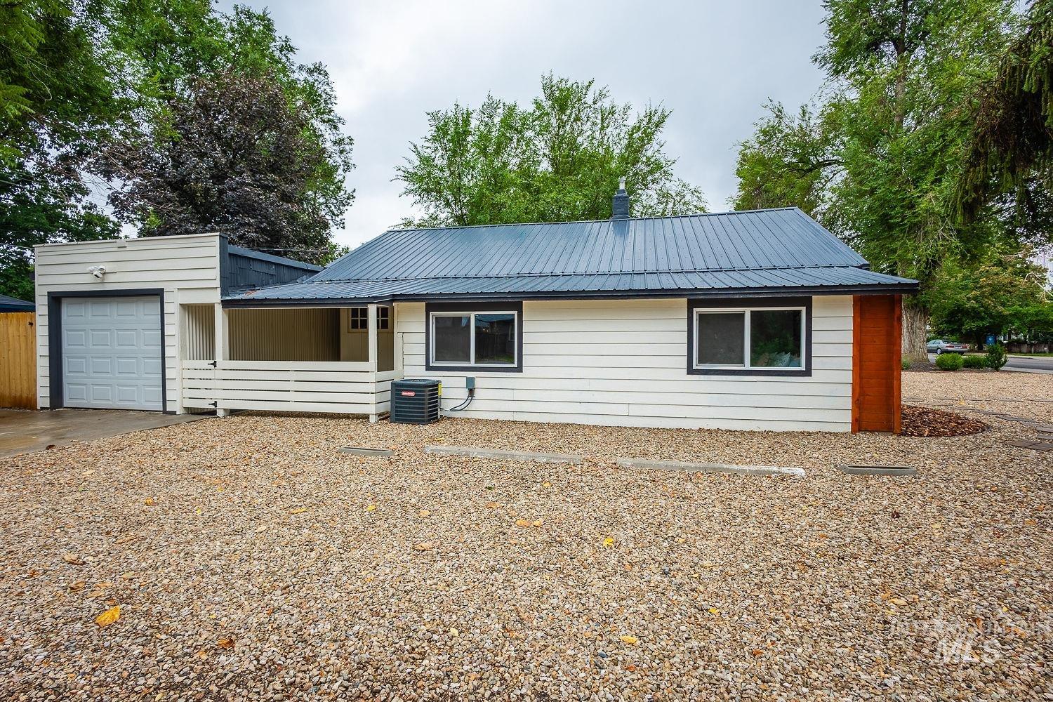 Rear view of house featuring a metal roof, an attached garage, and concrete driveway