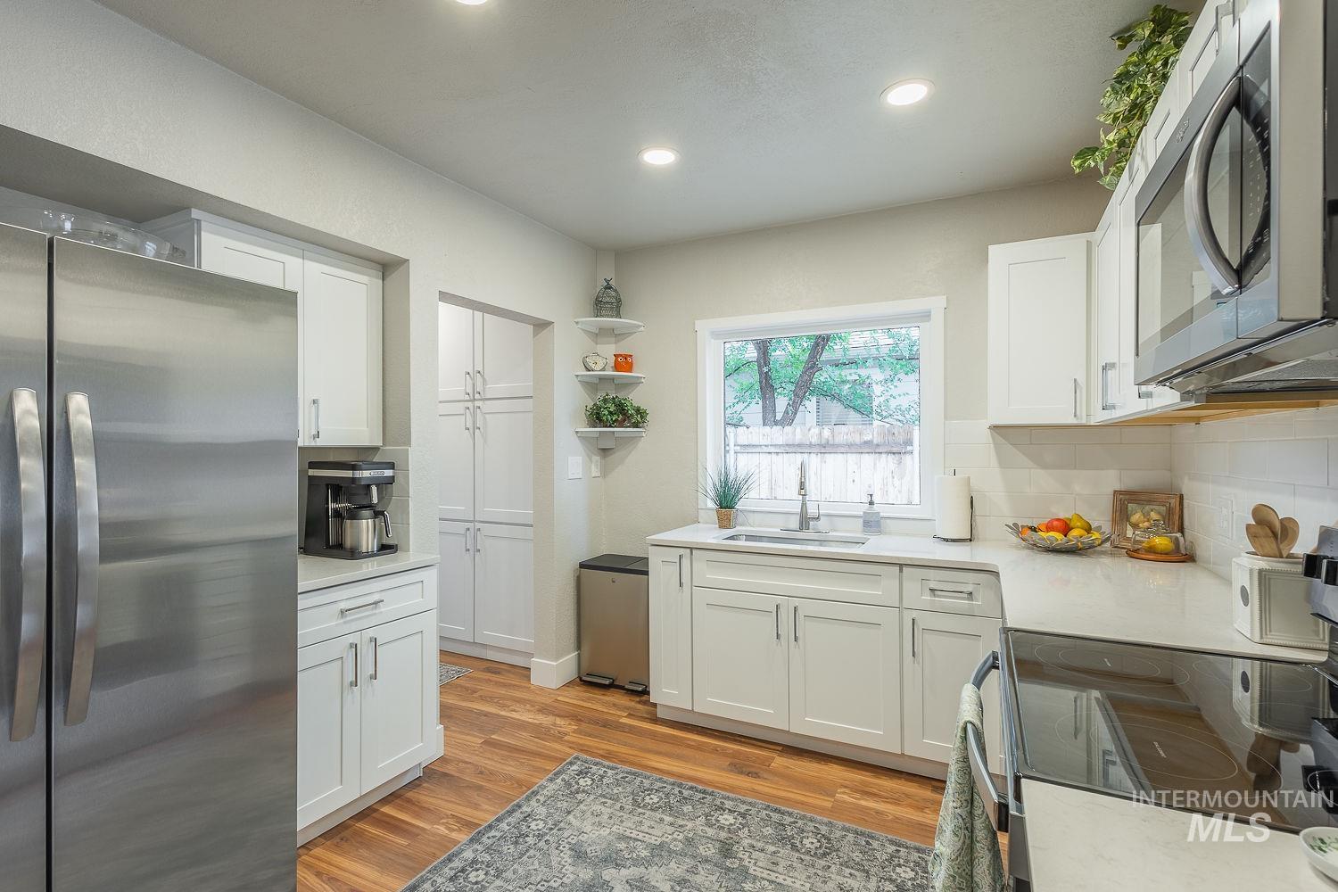 Kitchen featuring appliances with stainless steel finishes, white cabinetry, tasteful backsplash, open shelves, and recessed lighting