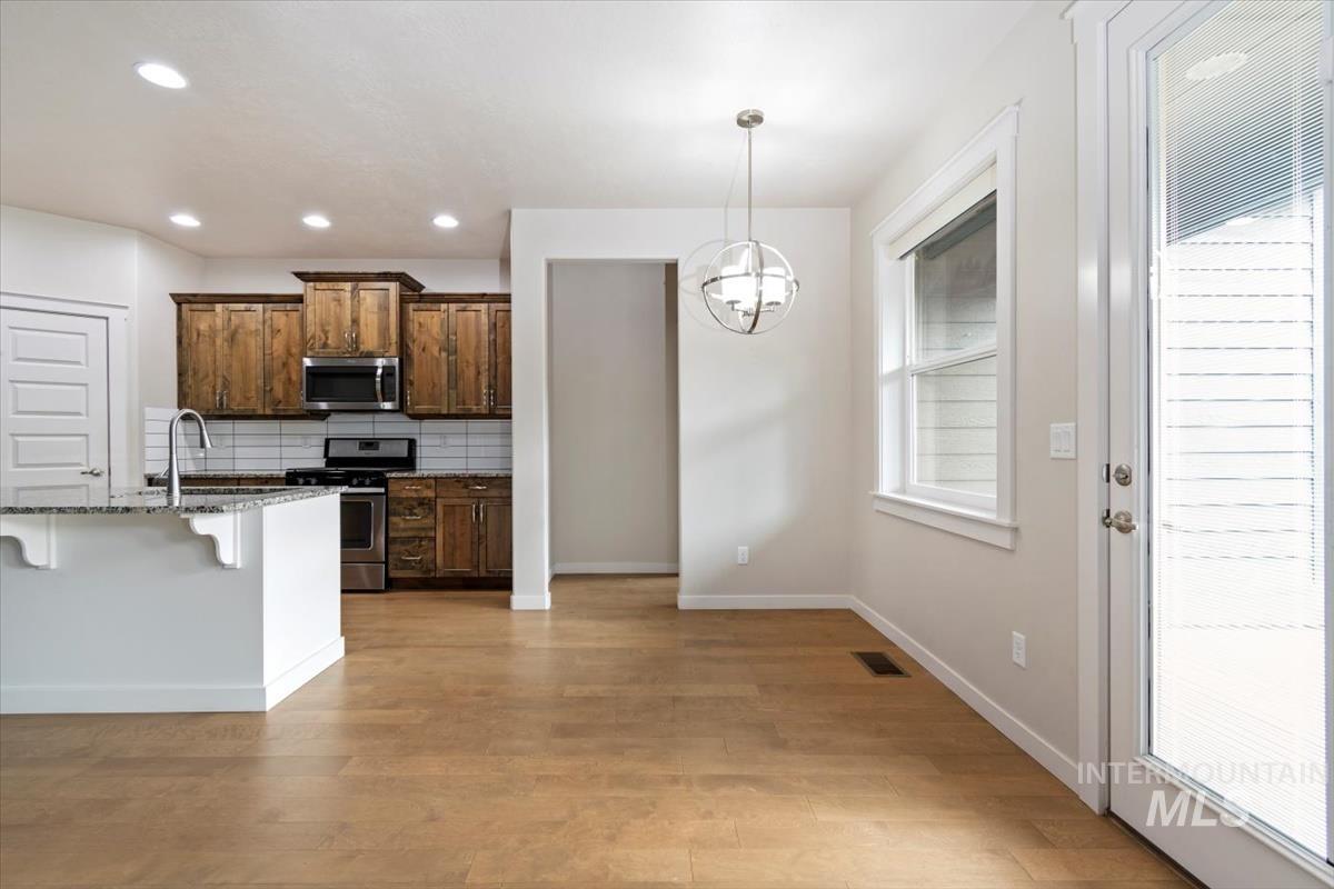 Kitchen with a kitchen bar, tasteful backsplash, pendant lighting, dark stone countertops, and appliances with stainless steel finishes