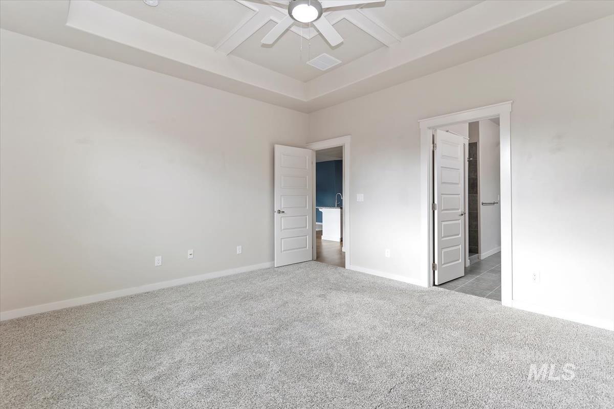 Unfurnished bedroom with coffered ceiling, light colored carpet, ceiling fan, beamed ceiling, and a raised ceiling