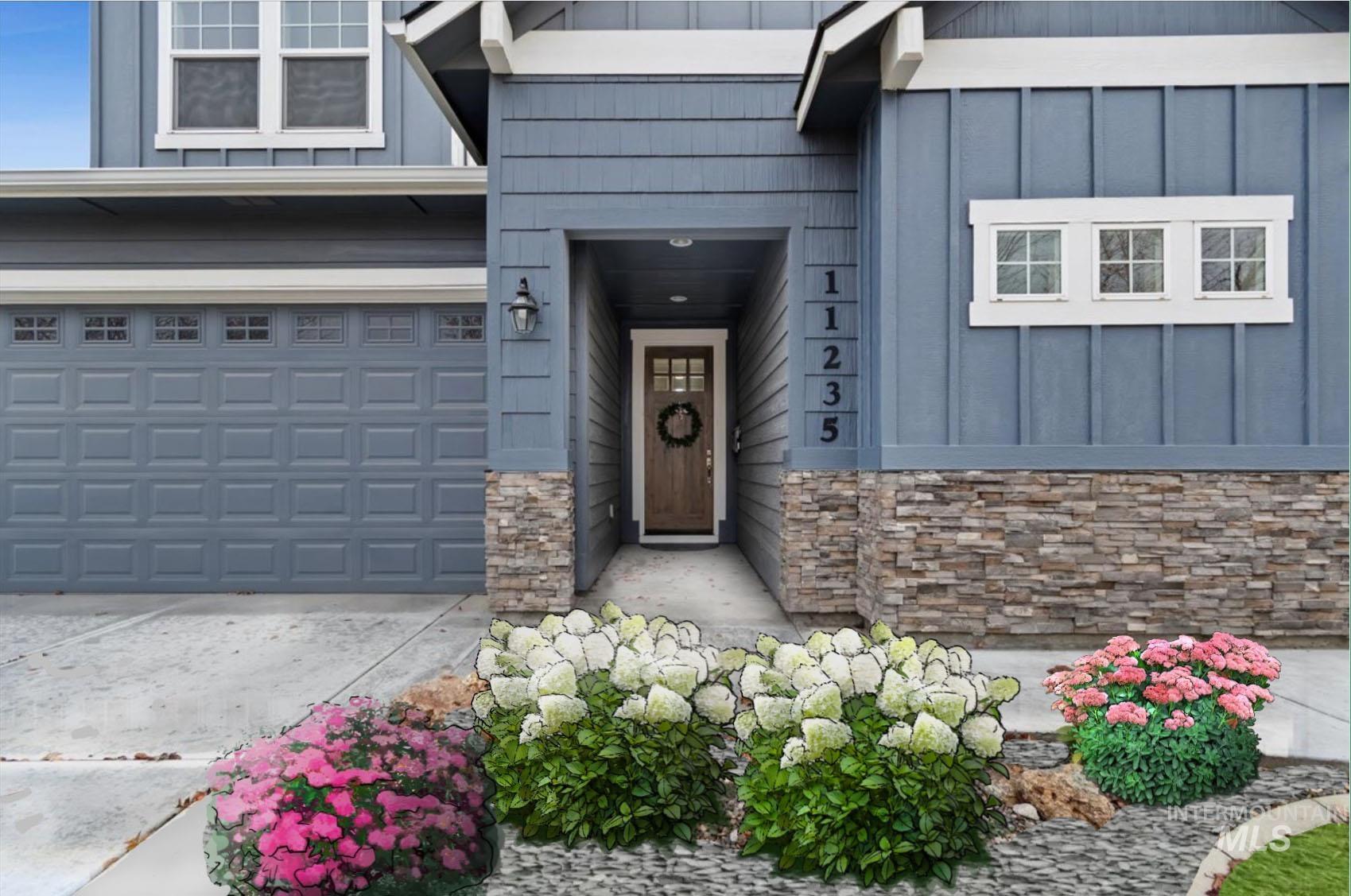 View of exterior entry featuring board and batten siding, stone siding, driveway, and a garage