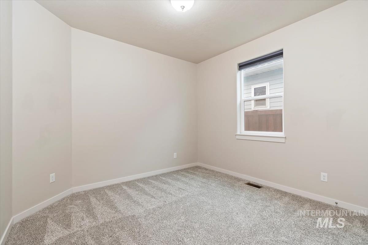 Spare room featuring carpet flooring and baseboards