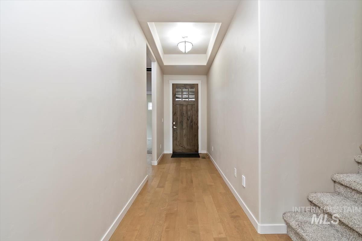 Doorway to outside with wood finished floors and a tray ceiling