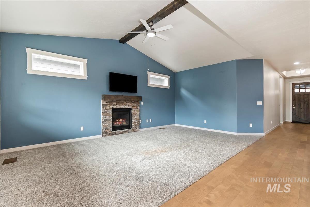 Unfurnished living room featuring a ceiling fan, a fireplace, carpet flooring, and wood finished floors