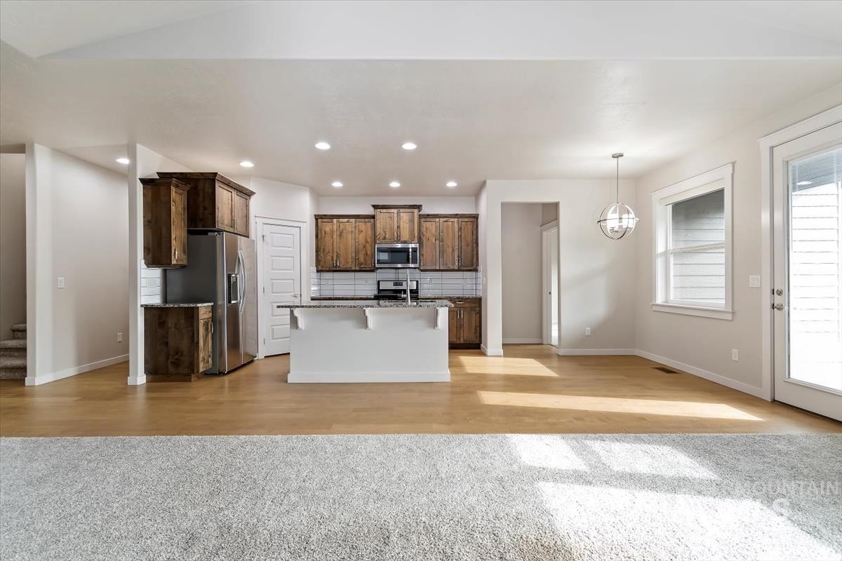 Kitchen with tasteful backsplash, a breakfast bar, open floor plan, light wood-style floors, and dark brown cabinets