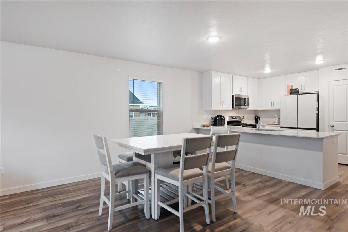 Dining space with dark wood-type flooring and baseboards
