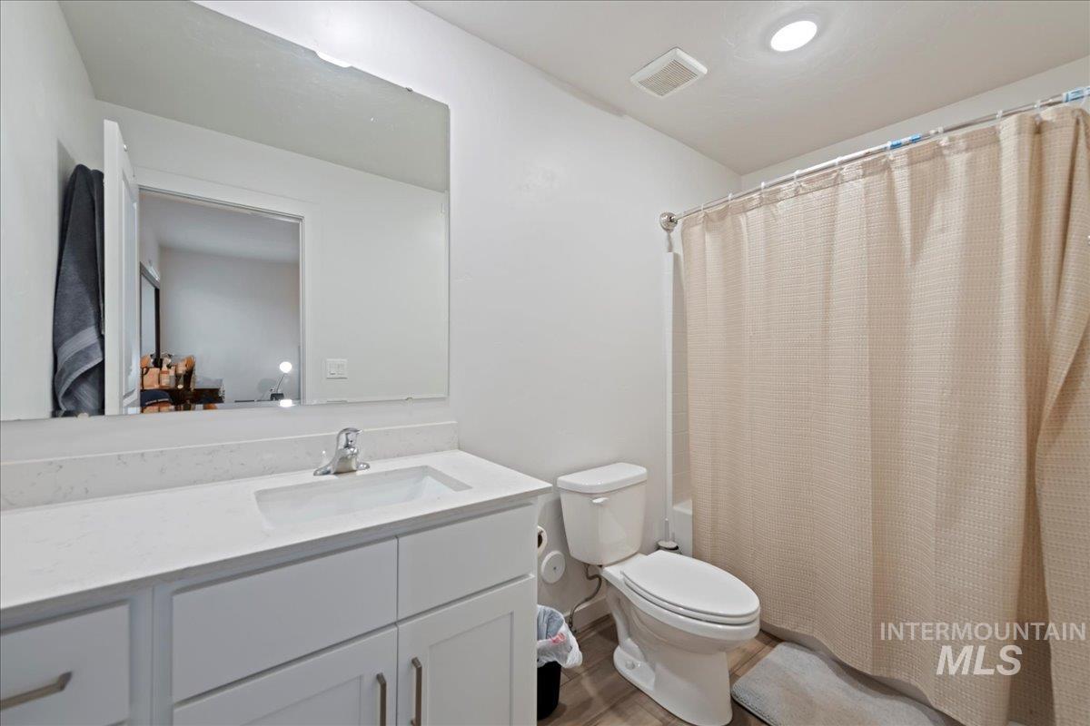 Bathroom with vanity, shower / bathtub combination with curtain, and light wood finished floors