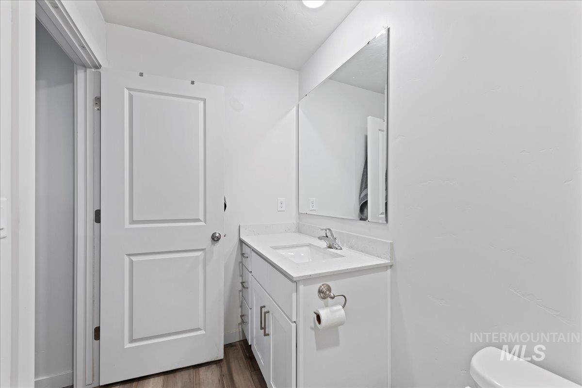 Half bathroom featuring vanity and dark wood finished floors