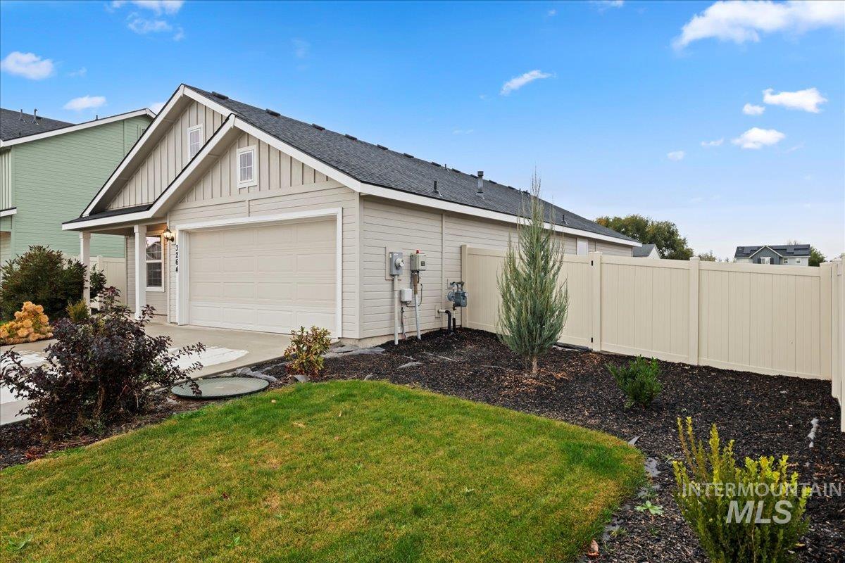 View of side of home featuring board and batten siding, roof with shingles, concrete driveway, and a garage