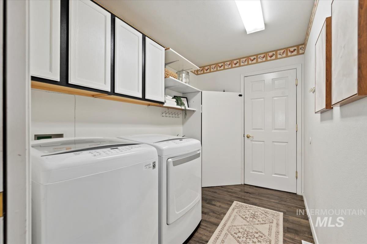 Washroom with dark wood-style flooring, cabinet space, and washer and clothes dryer