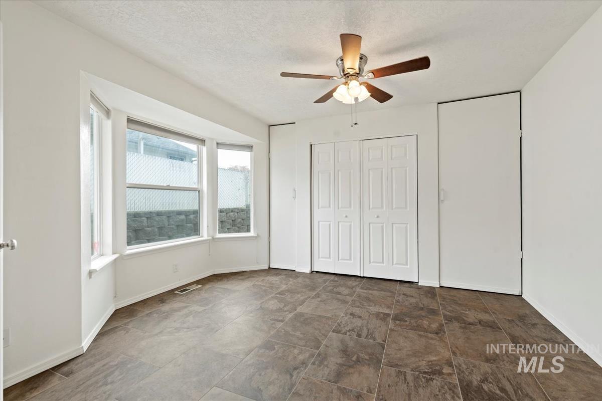 Unfurnished bedroom with ceiling fan, a textured ceiling, and a closet