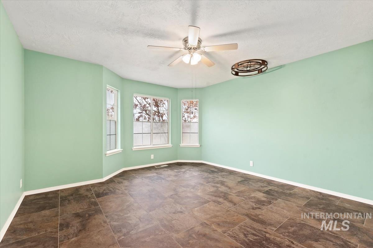 Spare room with a textured ceiling, a ceiling fan, and stone finish floors