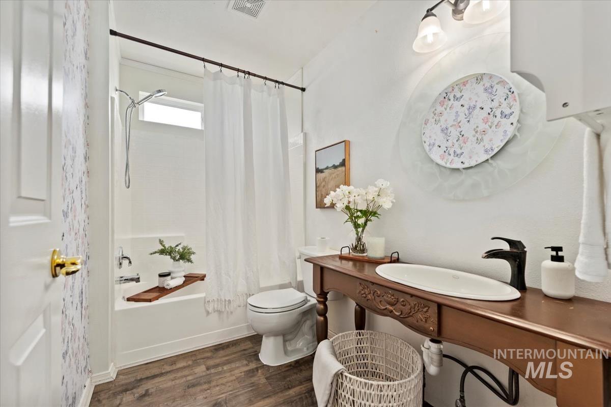 Full bathroom with shower / tub combo and dark wood-type flooring