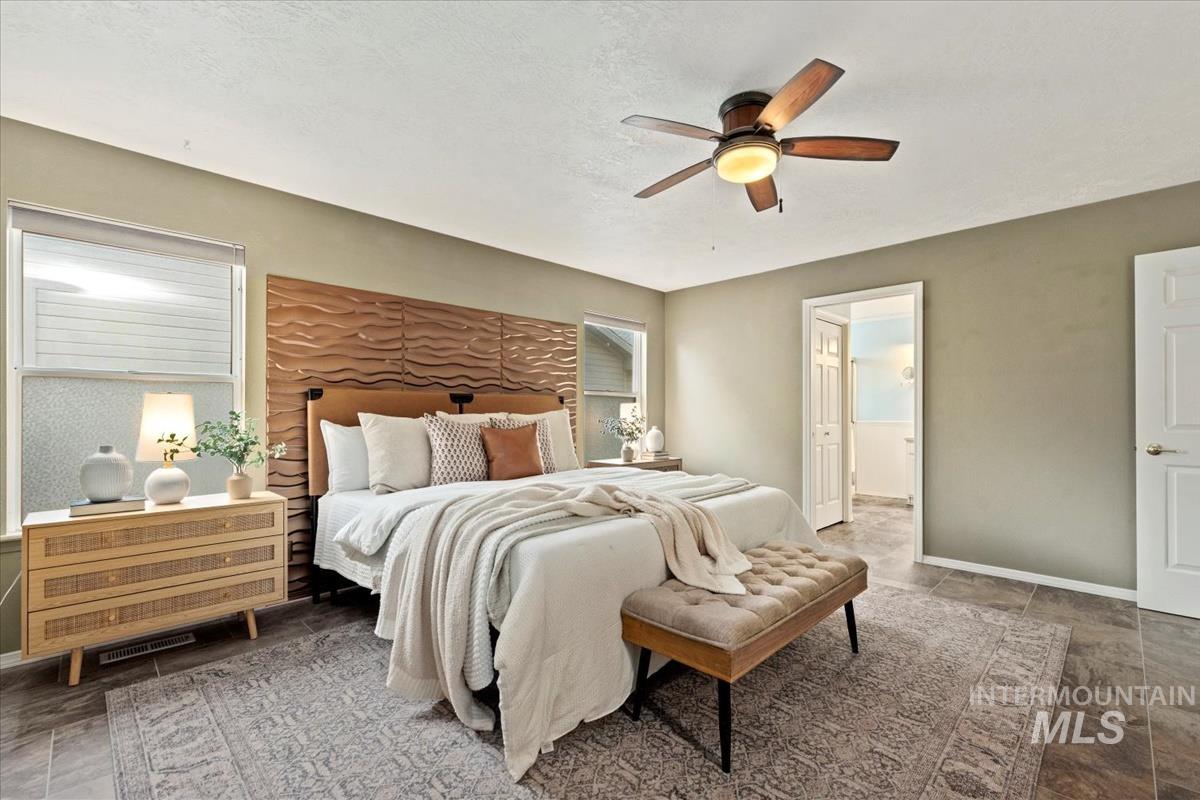 Bedroom featuring ceiling fan, a textured ceiling, and connected bathroom