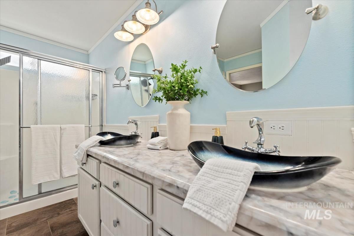 Full bath with crown molding, double vanity, and a stall shower
