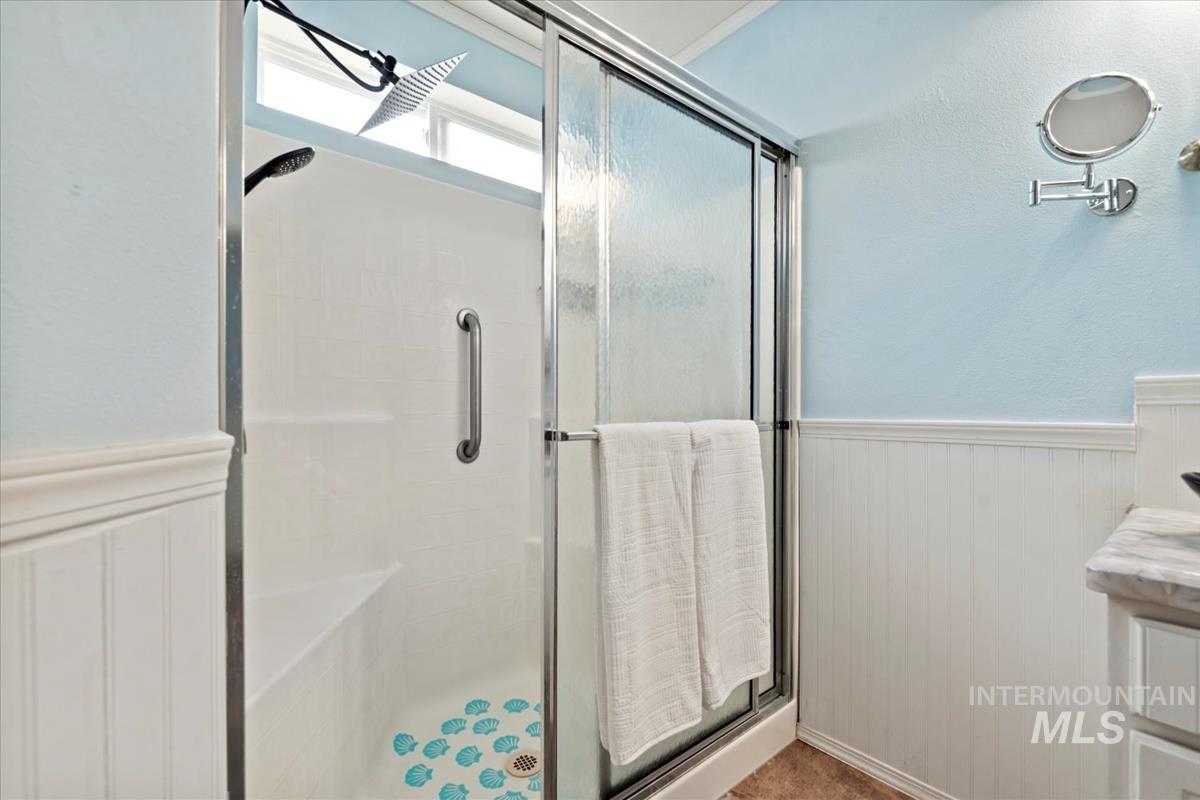 Bathroom featuring wainscoting, vanity, a stall shower, and a textured wall