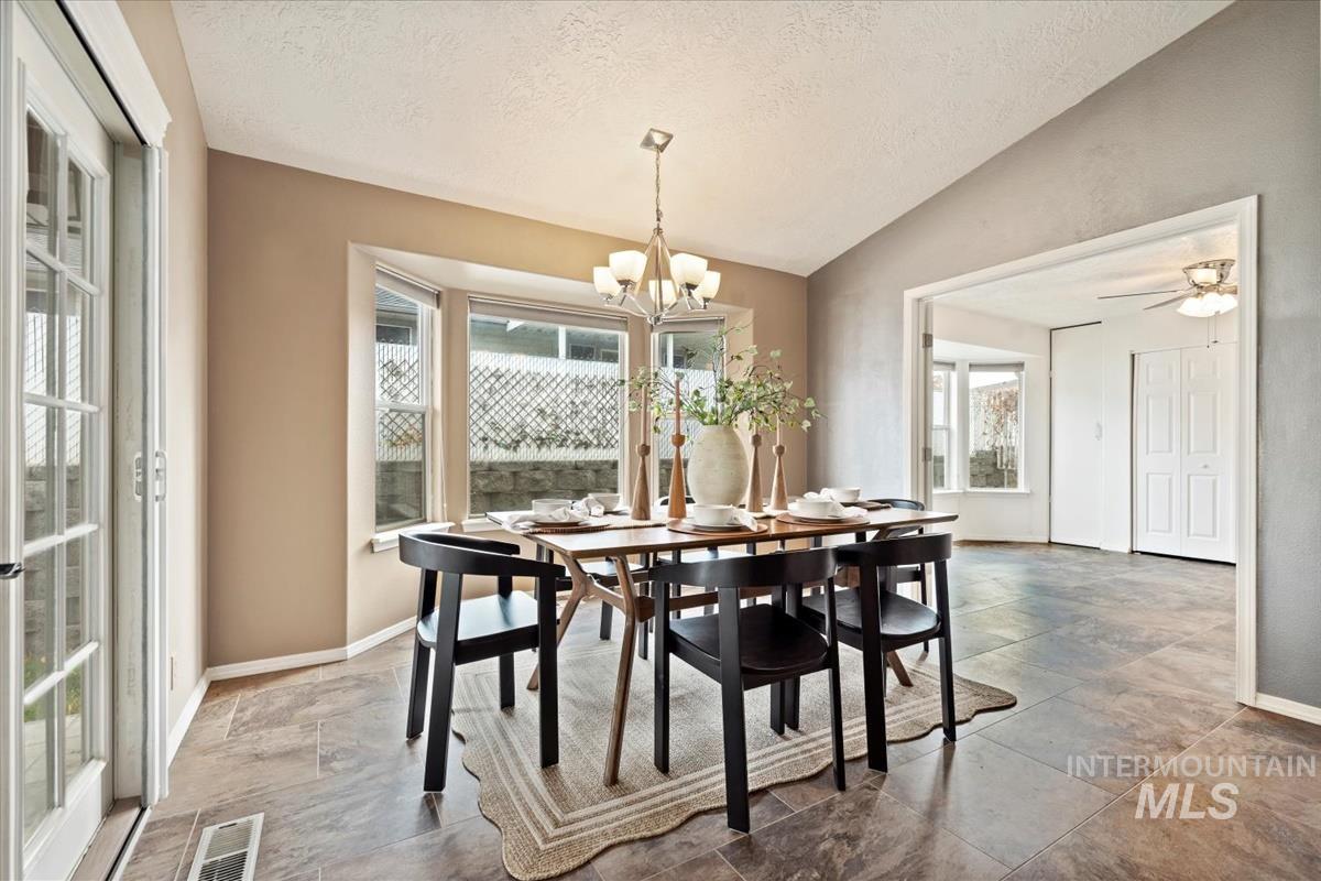Dining area with lofted ceiling, a textured ceiling, ceiling fan, and a chandelier