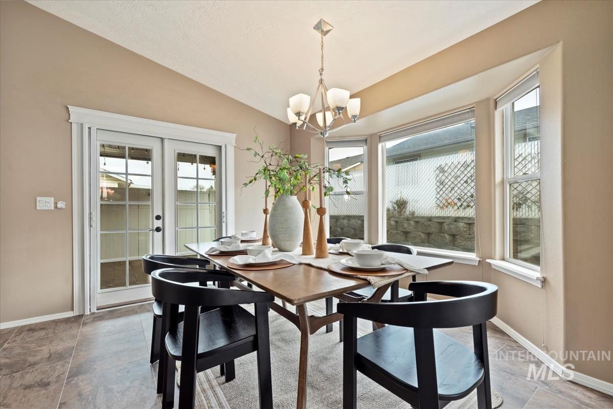 Dining area featuring lofted ceiling, french doors, and a chandelier