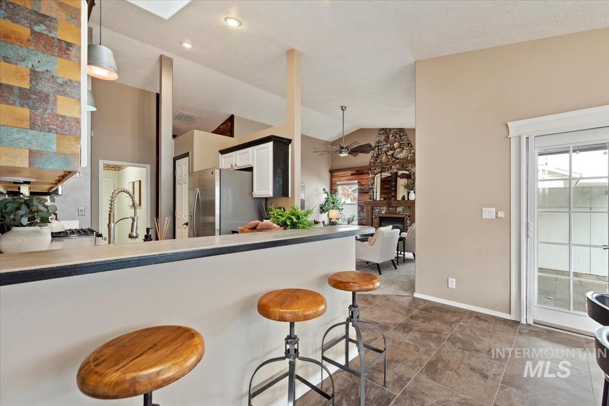 Kitchen featuring a kitchen breakfast bar, a fireplace, lofted ceiling, a peninsula, and light countertops